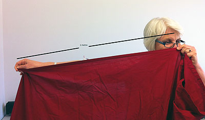 Person holding a piece of material from outstretched hand to nose with head averted. Length of material marked as 1 metre.